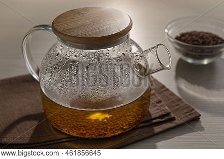 Glass Teapot With Aromatic Buckwheat Tea And Granules On Wooden Table, Closeup