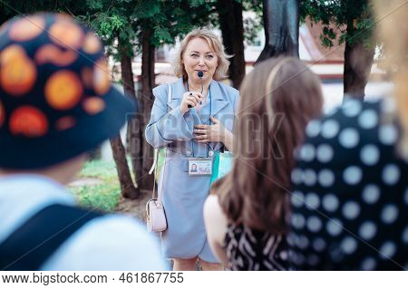 Female Guide Is Telling A Group Of Tourists About Something.