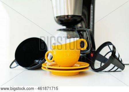 An Automatic Drip Coffee Maker Stands With A Yellow Cup On A White Table. Black Modern Drip Coffee P