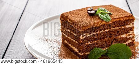 Tiramisu Dessert Decorated With Mint On White Plate. Slice Of Coffee Cake On Light Background. Tradi