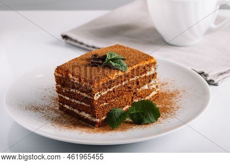 Tiramisu Dessert And Coffee Cup On Light Background. Tiramisu Cake Decorated With Mint Leaves. Slice
