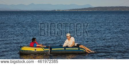 Young Couiple On Water Attractions During Summer Vacations. Woman And A Man Ride On An Inflatable Bo