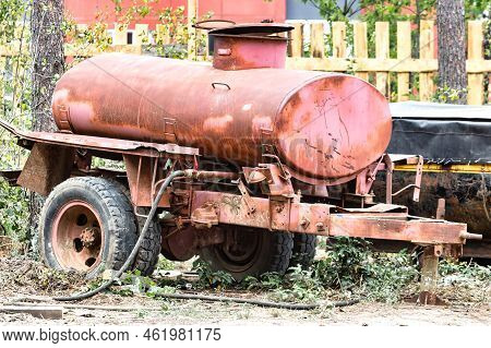 An Old Barrel On Wheels For Watering And Delivering Water To A Construction Site. Temporary Water Su