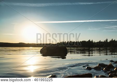 Lake In Sweden, Smalland At Sunset With Rock In Foreground Of Water With Forest In Background. Lands