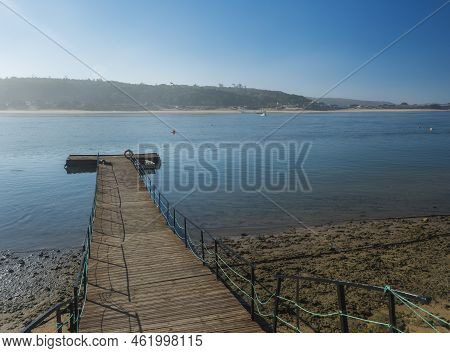 Small Wooden Boat Dock, Pier For Ferry Boats Across The River Mira Flowing Into The Atlantic Ocean. 
