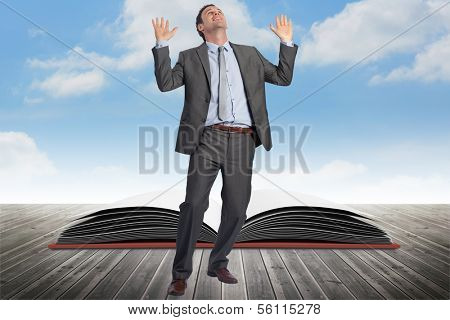 Businessman posing with arms raised against open book against sky