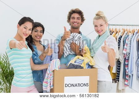 Group of young people with clothes donation gesturing thumbs up