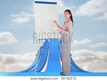 Businesswoman painting on an easel against blue abstract design in room