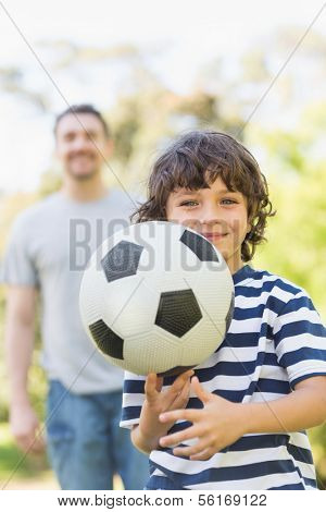 Portrait of a father and son playing football in the park