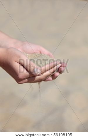 A person holding dry sand in her hands.