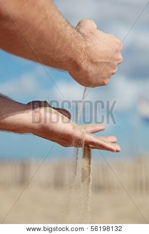 A person holding dry sand in his hands.