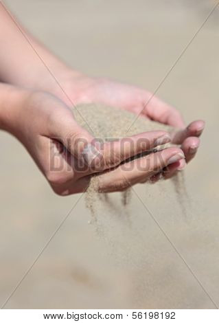 A person holding dry sand in his hands.