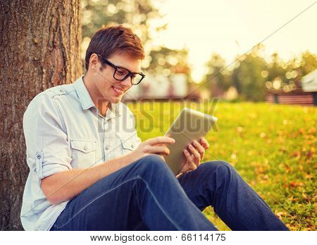 education, technology and internet concept - smiling male student in eyeglasses with tablet pc outside