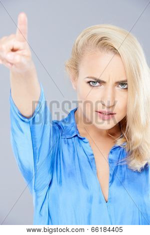 Angry beautiful blond woman frowning as she points away with her finger ordering someone to leave