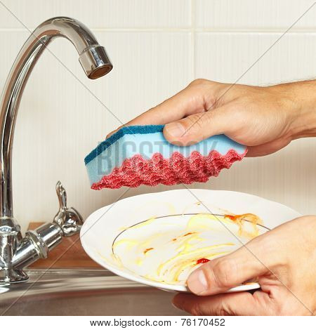 Hands with sponge and dirty plate over the sink in kitchen