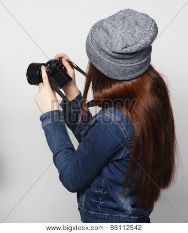 Beautiful young woman with camera over gray background