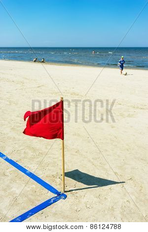 Red Flag On The Beach And A Boy With A Ball