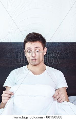 Good Looking Young Man In Bed Looking Down At His Penis Under White Covers