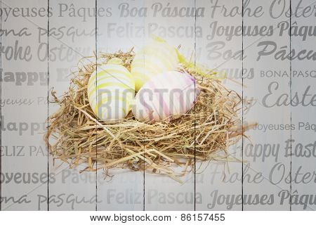 Happy easter in different languages against three easter eggs in straw