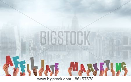hands holding up affiliate marketing against room with large window looking on city