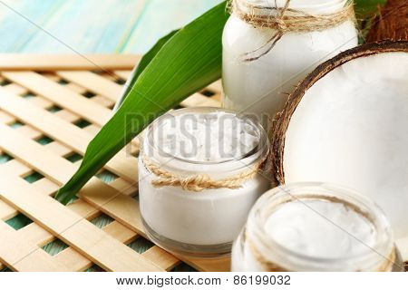 Fresh coconut oil in glassware on color wooden table and grid tray background