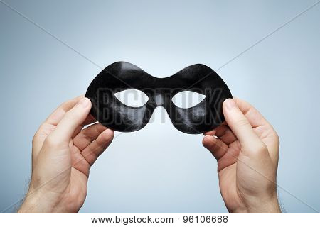 Man holding a black eye mask in his hands.