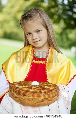 Little girl is dressed in the Russian national dress. She holds in his hands the fresh loaf. It is a custom to meet the guests.