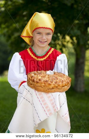 Little girl is dressed in the Russian national dress. She holds in his hands the fresh loaf. It is a custom to meet the guests.