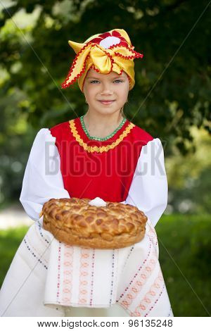 Little girl is dressed in the Russian national dress. She holds in his hands the fresh loaf. It is a custom to meet the guests.