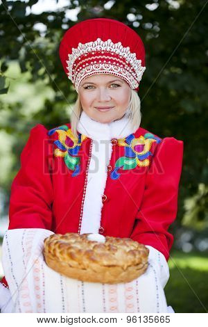 Young woman is dressed in the Russian national dress. She holds in his hands the fresh loaf. It is a custom to meet the guests.