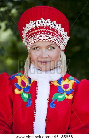 Close up young woman is dressed in the Russian national dress in summer park