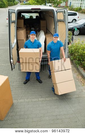 Two Workers Loading Cardboard Boxes In Truck