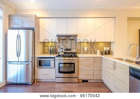 Modern, bright, clean, kitchen interior with stainless steel appliances in a luxury house.