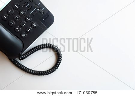 Top view or flat lay of digital voip black telephone on white table call center contact center customer service customer support concept background with copy space selective focus on dialing pad
