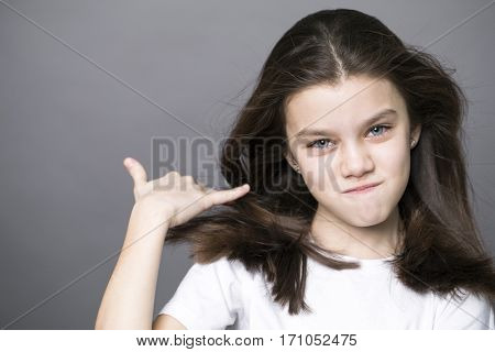 Sign Call me. Pretty brunette litte girl, isolated on gray background