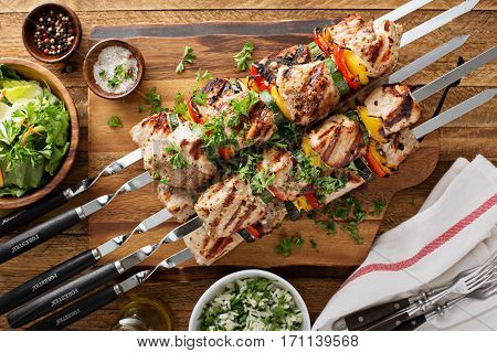 Pork and vegetables cabobs on the cutting board with fresh herbs
