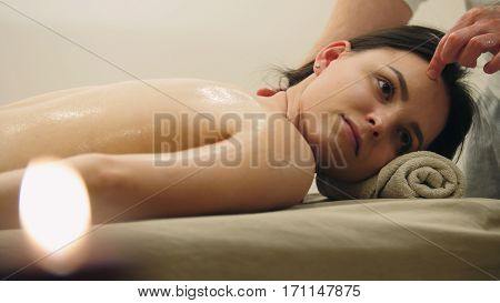 Young woman having classical massage in beauty spa, sesame oil, telephoto