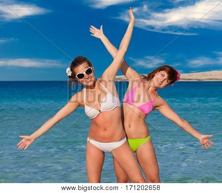 Two woman in bikini is having fun near blue sea
