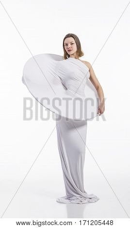 A young,smiling girl in the conceptual white dress on a white background . Studio photography .