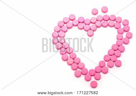 Heart shape of pink pills on white background. Tablets of drug for asthma treatment.
