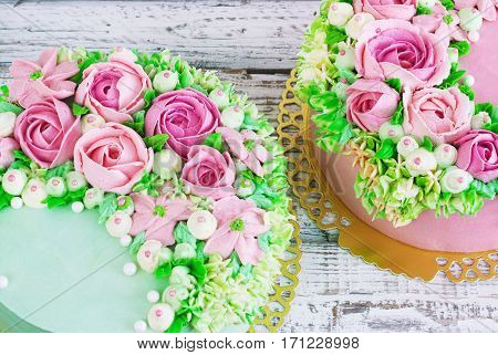 Two celebratory cake with flowers rose on a white wooden background.