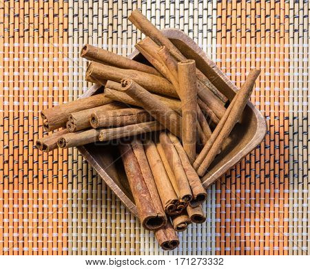 Oriental fragrant cinnamon sticks in wooden bowl