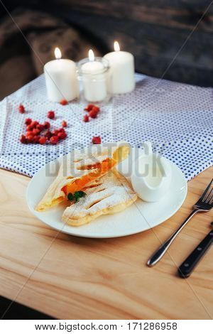 piece of freshly baked pumpkin strudel home with powdered sugar and cream and a sprig of mint
