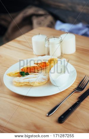piece of freshly baked pumpkin strudel home with powdered sugar and cream and a sprig of mint