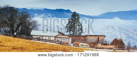 Wooden old house in the mountains in a foggy weather.