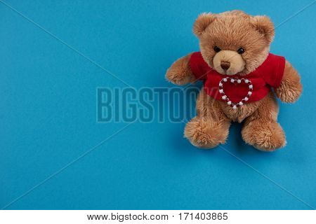 Teddy bear soft toy on blue background Love card concept with copy space. Valentine's day theme