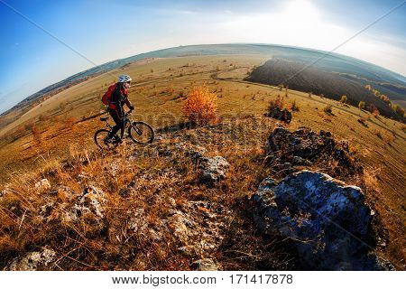 Mountain biker riding on bike at summer mountains. Man rider cycling MTB on countrysied road or single track. Sport fitness motivation, inspiration in beautiful inspirational landscape. Hill and blue sky. Helmet. backpack, sunglasses.