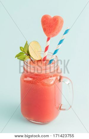 Sweet watermelon smoothie in Mason jar with straws, mint, lime decorated watermelon slice curved like heart symbol