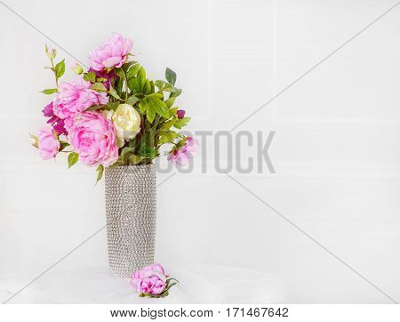 Pink flowers in silver vase on white wall background. 8 March. Happy women's day.