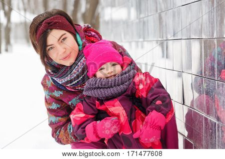 Portrait of woman and daughter in winter park near building
